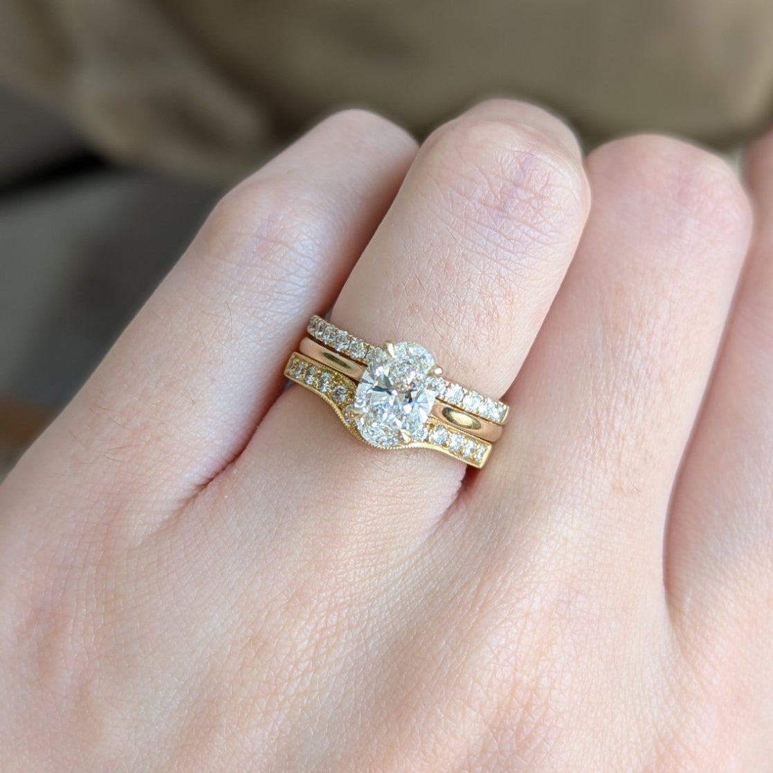 Close-up of a hand wearing a gold ring with a diamond on a blurred background