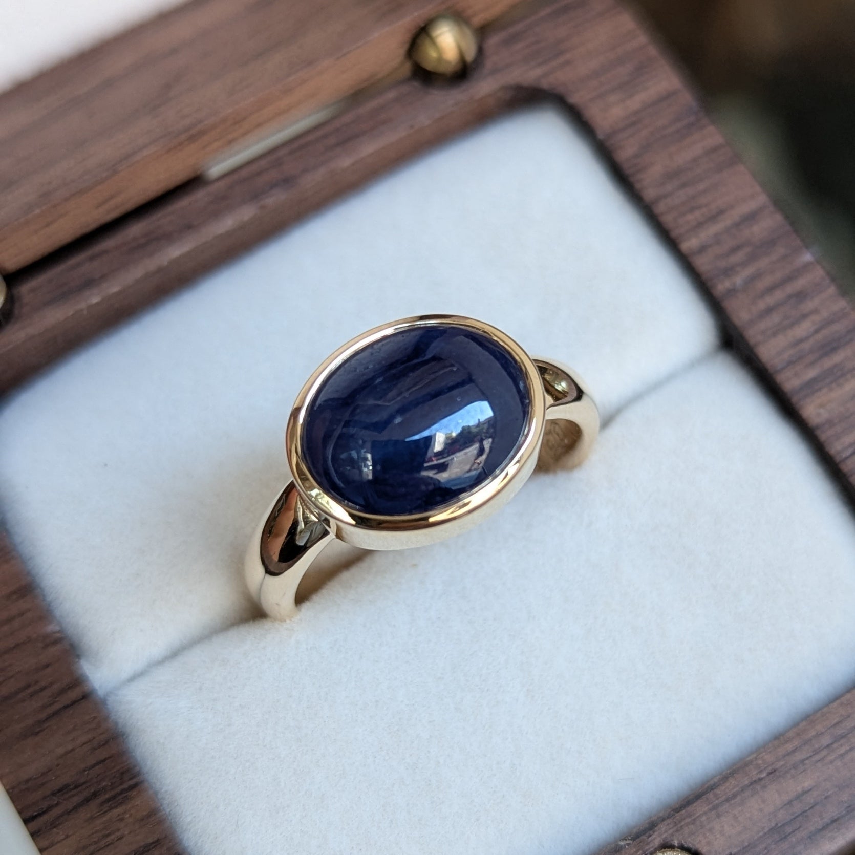 Gold ring with a blue Sapphire in a wooden box