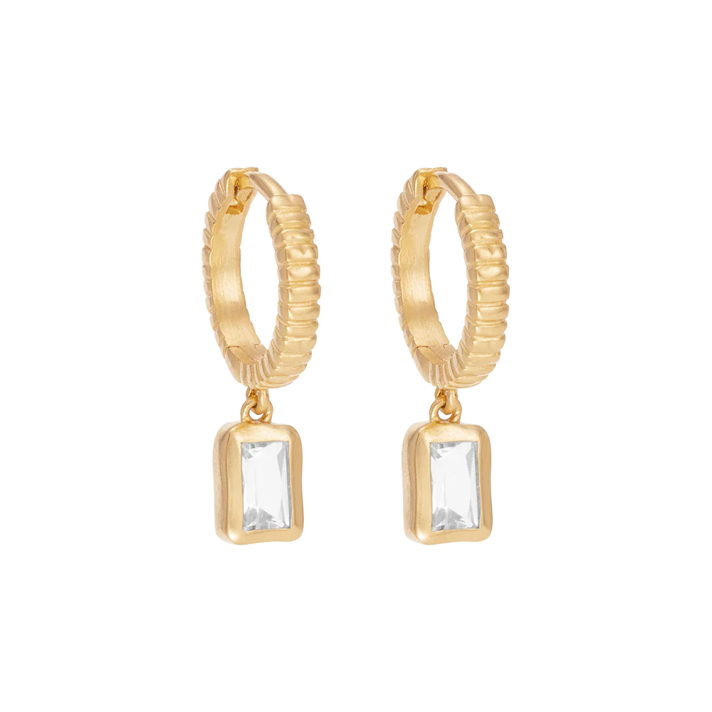 Gold hoop earrings with emerald cut topaz on a white background