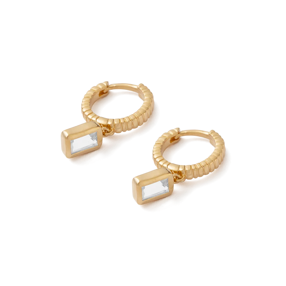 Gold hoop earrings with emerald cut topaz on a white background