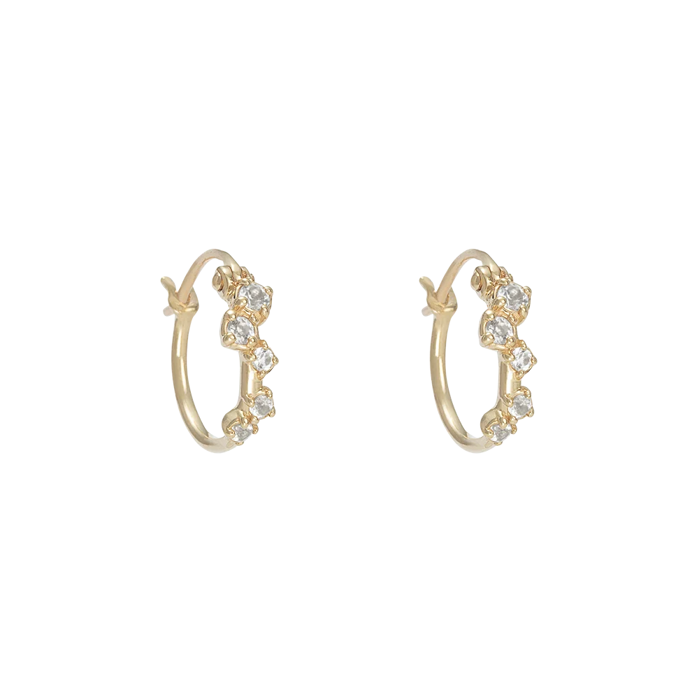 A pair of gold hoop earrings with a row of round topaz, displayed on a solid white background.