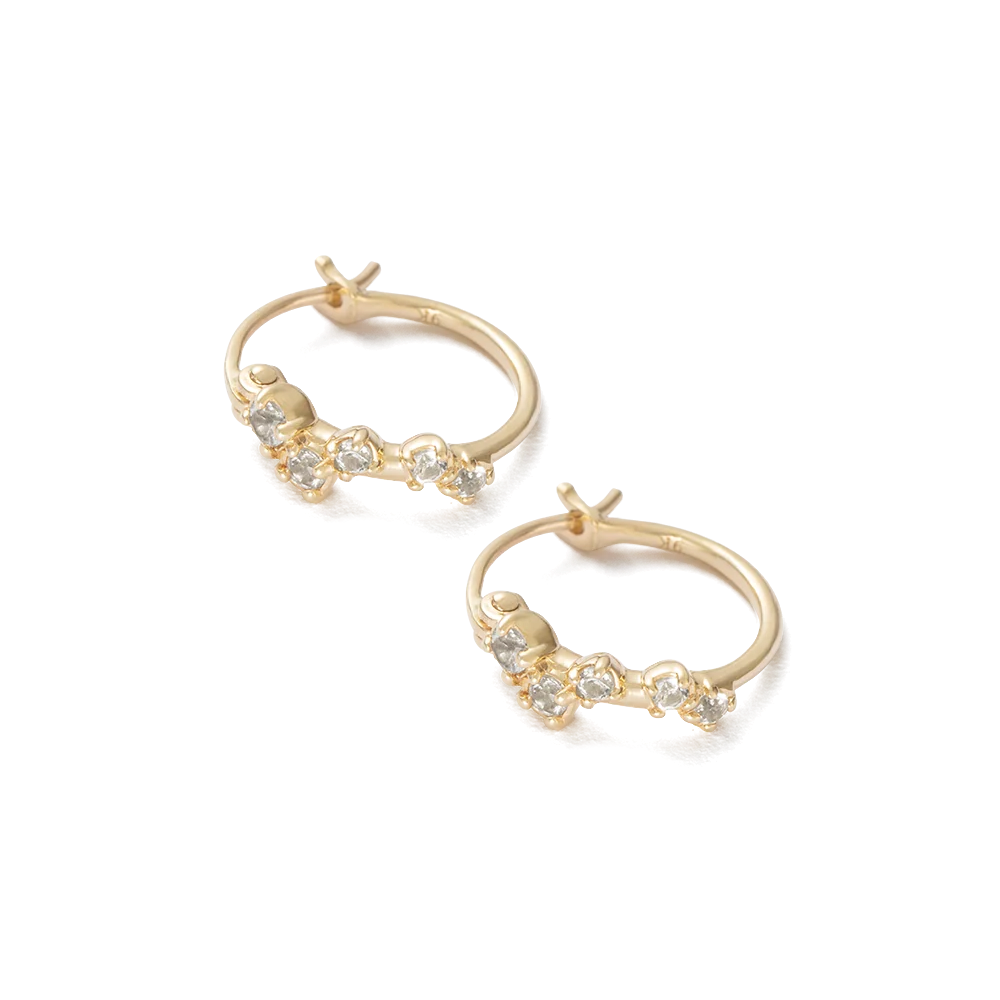 A pair of gold huggie hoop earrings with small white topaz along the front, displayed on a clean white background.